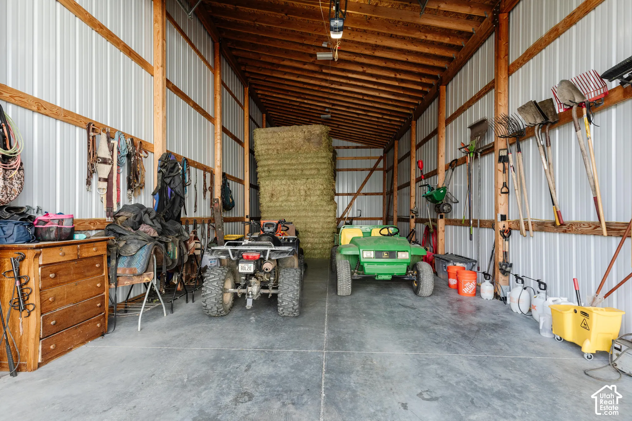 Spacious outbuilding featuring exposed wood-post framing, corrugated metal wall paneling, and a concrete slab floor