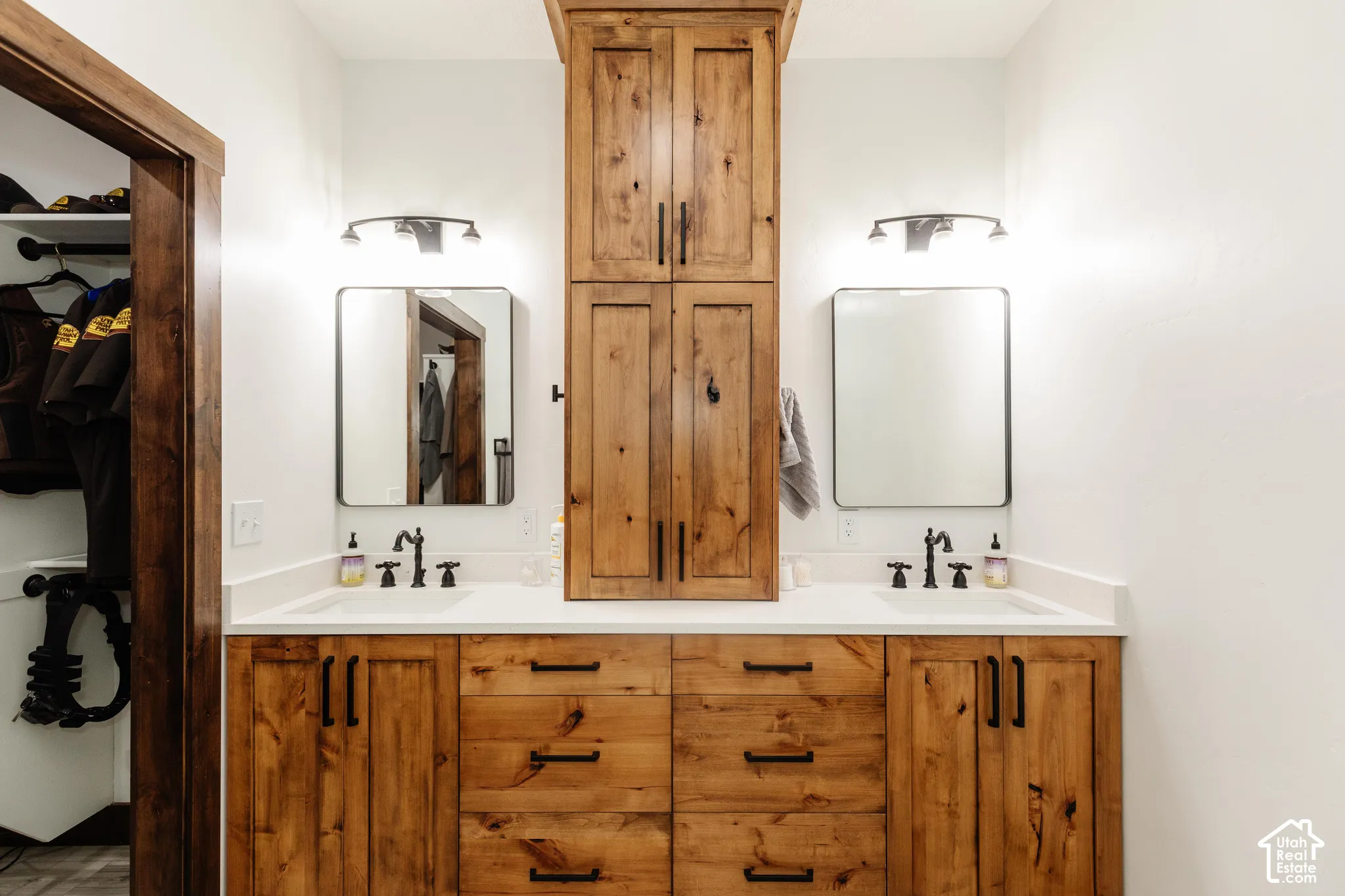 Custom wood cabinetry with central tower storage, dual undermount sinks, quartz countertop, and matte black fixtures