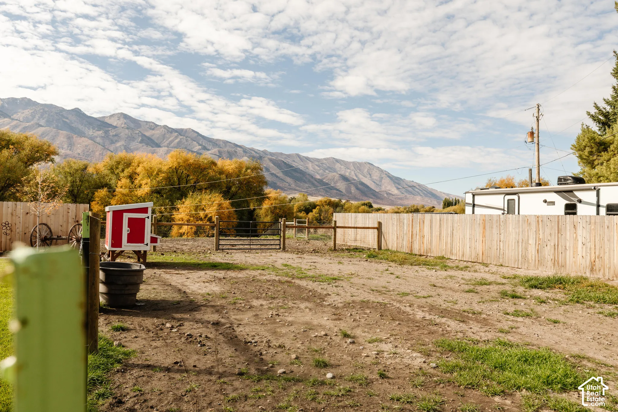 Open-air lot featuring perimeter wood fencing, a metal gate, and mountain scenery