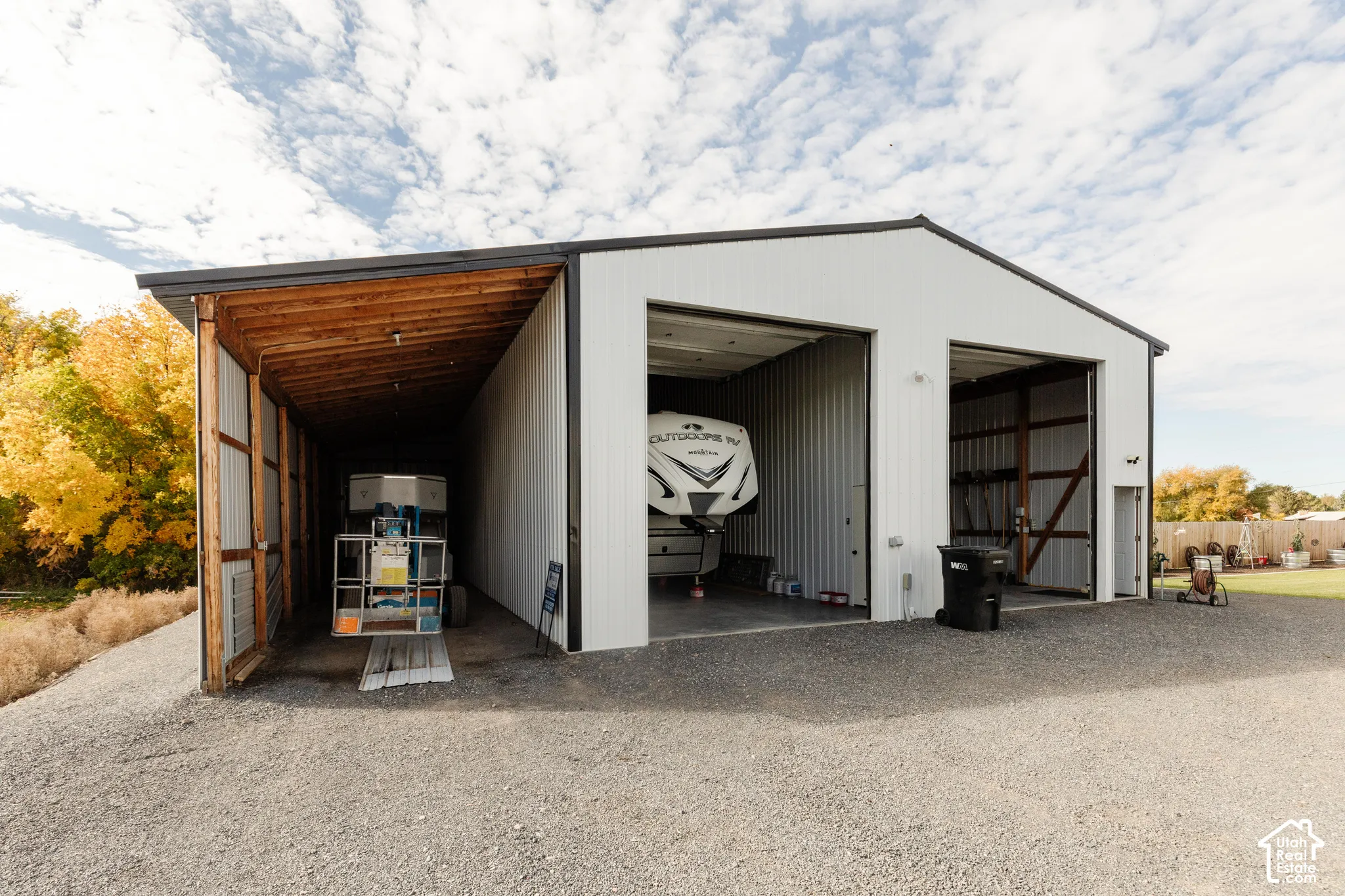 Metal-clad detached workshop featuring dual bay doors and an attached open-sided storage shelter