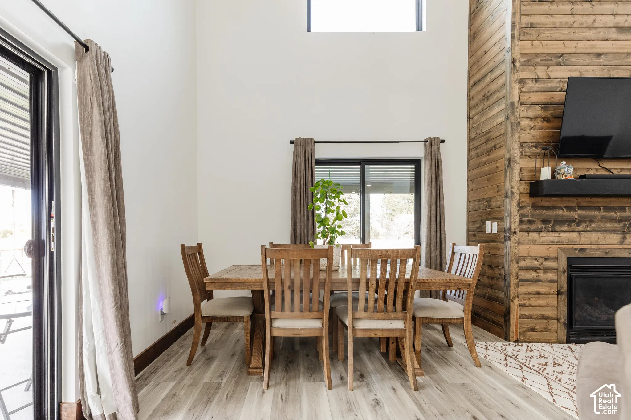 Vaulted ceilings, wood-finish flooring, floor-to-ceiling wood-plank accent wall, and a fireplace with a built-in mantle