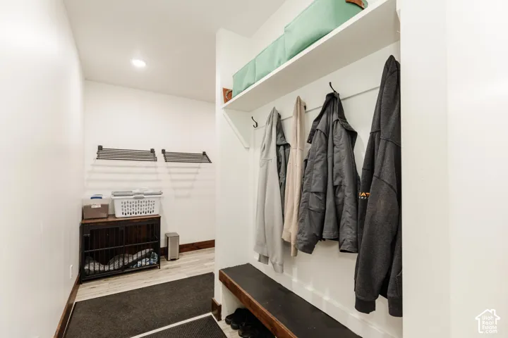 Built-in wooden bench seating, wall-mounted coat hooks, and an integrated overhead storage shelf