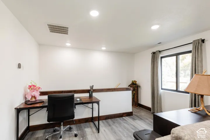 Wood-finish flooring, recessed lighting, and dark-stained wood trim accents