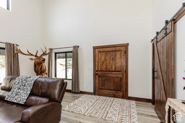 High-ceiling interior featuring a stained wood entry door, matching wood-finish barn-style sliding door, and wood-finish flooring