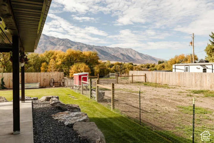 Covered concrete patio featuring rock landscaping, wooden perimeter fencing, and mountain scenery