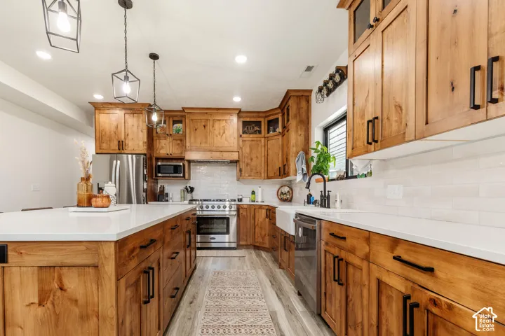 Kitchen featuring wood cabinetry, stone countertops, a farmhouse-style sink, stainless steel appliances, and matte black hardware