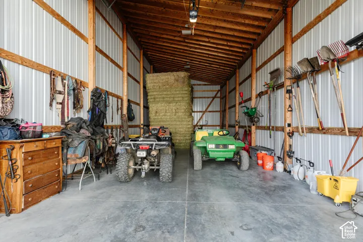 Spacious outbuilding featuring exposed wood-post framing, corrugated metal wall paneling, and a concrete slab floor