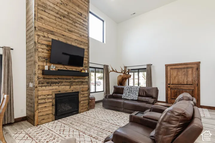 Floor-to-ceiling wood-plank fireplace surround, vaulted ceiling, wood-finish flooring, and solid wood interior door