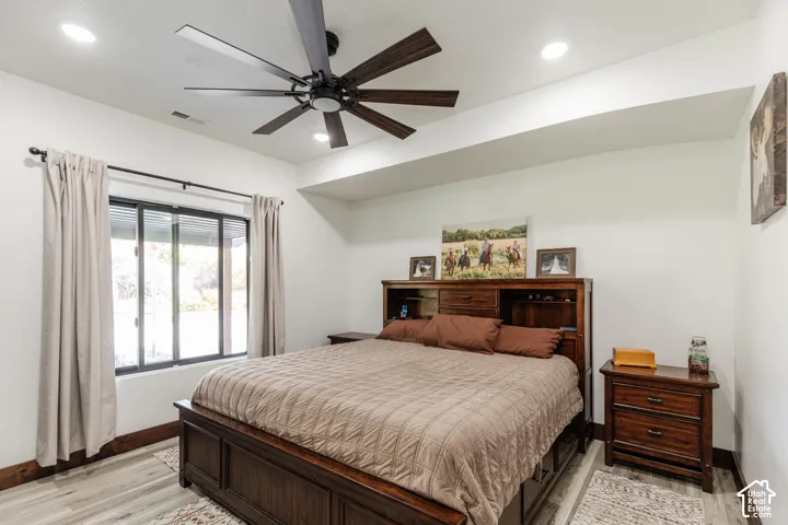 Neutral-toned room featuring a multi-blade ceiling fan, recessed lighting, wood-finish flooring, and large windows with horizontal-slid glass panes