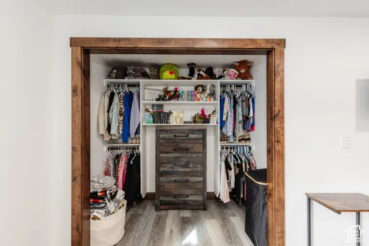 Reach-in closet featuring custom white built-in shelving, a centrally located integrated five-drawer dresser, and natural wood-finish trim casing