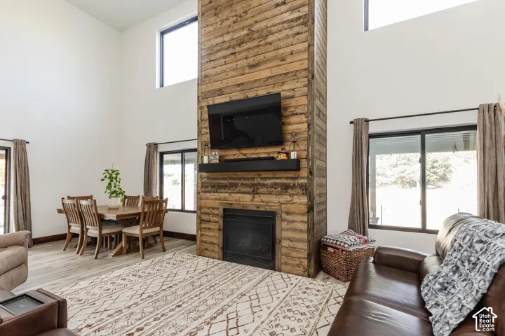 Double-height ceiling, floor-to-ceiling wood-plank fireplace surround, built-in black mantel, and wood-finish flooring