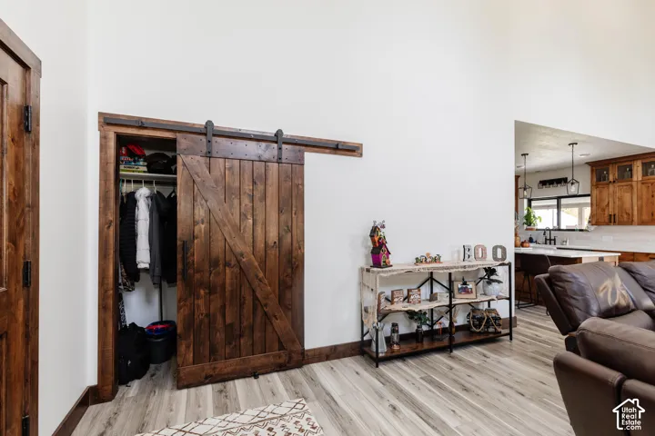Wood-finish barn door with matte black hardware, high ceilings, and wood-finish flooring
