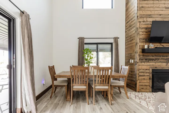 Vaulted ceilings, wood-finish flooring, floor-to-ceiling wood-plank accent wall, and a fireplace with a built-in mantle