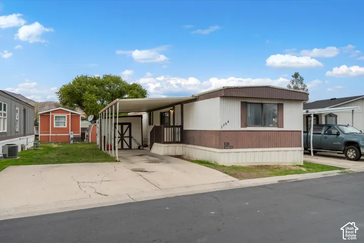 Exterior featuring a two-tone facade, concrete driveway, attached metal carport, and a detached storage shed