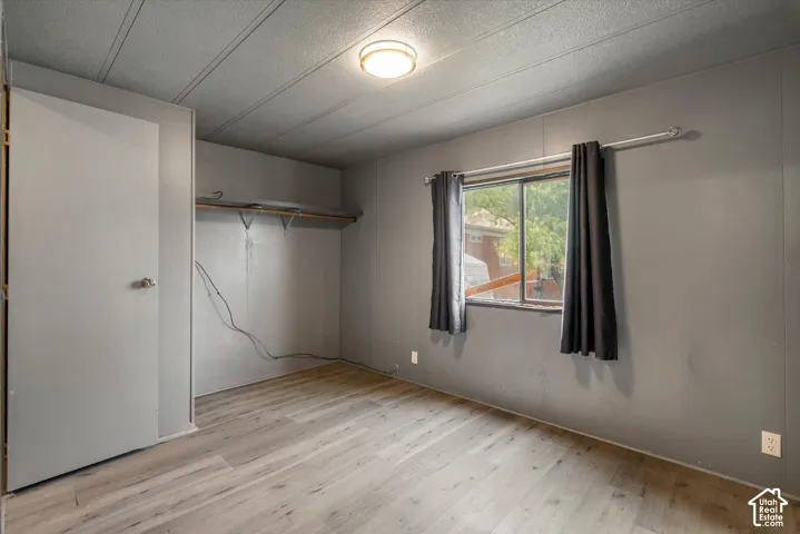 Room featuring wood-finish flooring, a sliding window, built-in shelving, and a flush-mount ceiling light fixture