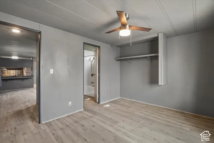 Interior space featuring wood-finish flooring, a ceiling fan with integrated lighting, and built-in closet shelving