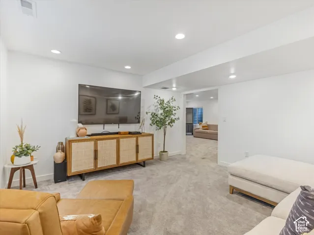 Neutral interior space featuring recessed ceiling lighting, light-toned wall-to-wall carpeting, and crisp white wall finishes