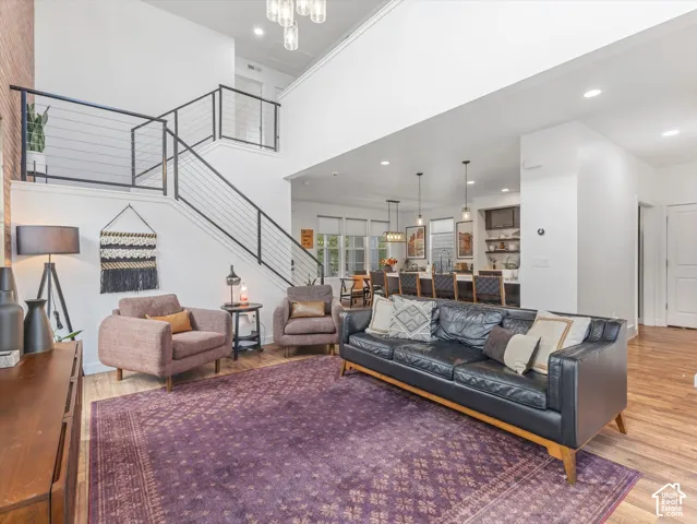 Open-concept area featuring a two-story ceiling, a staircase with horizontal cable railing, wood-finish flooring, and recessed lighting