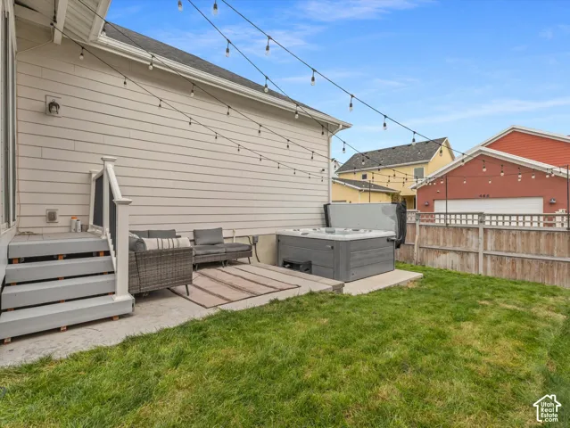 Rear yard featuring a concrete patio, integrated hot tub, and wood-style perimeter fencing