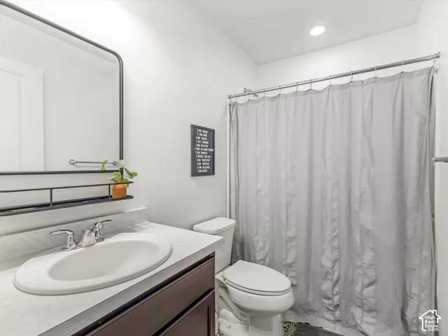 Bathroom featuring a dark wood-finish vanity, light-toned countertop with an integrated oval sink, chrome-finish faucet, framed mirror with integrated storage shelving, and a shower-tub combination