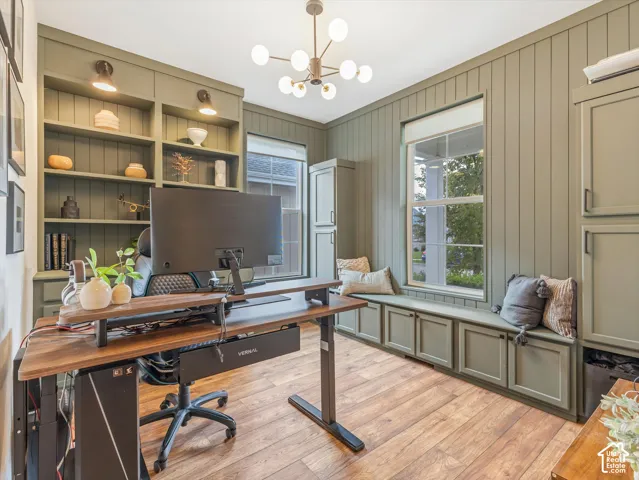Custom floor-to-ceiling built-in cabinetry with integrated shelving and bench seating, wood-finish flooring, vertical panel wall detailing, and a multi-arm modern light fixture
