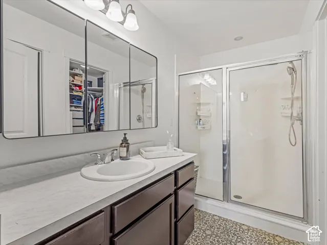 Bathroom featuring a vanity with a light-toned countertop, integrated basin, and full-width tri-fold medicine cabinet