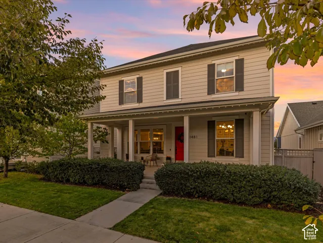 Two-story residence featuring horizontal siding, a full-width covered front porch, dark-tone exterior shutters, and a concrete walkway