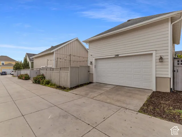 Two-car garage with horizontal siding, concrete driveway, and exterior wall-mounted carriage lighting