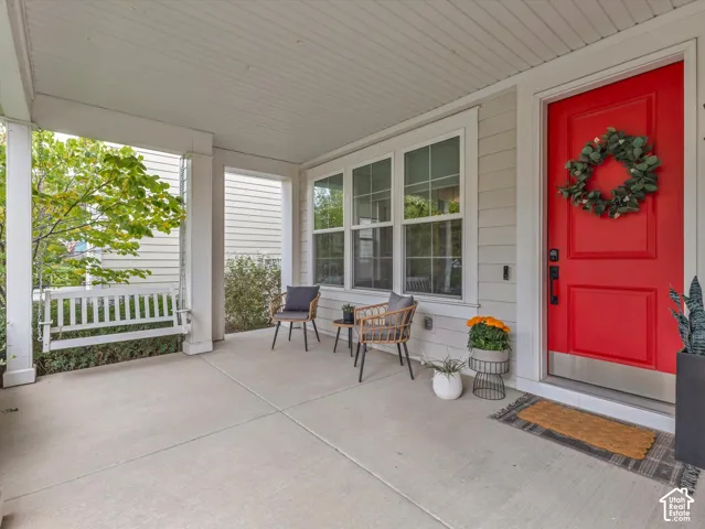 Covered front porch featuring a concrete floor, built-in porch swing, lap siding, and a paneled entry door