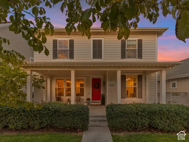 Two-story exterior featuring horizontal siding, a covered front porch with square columns, and window shutters