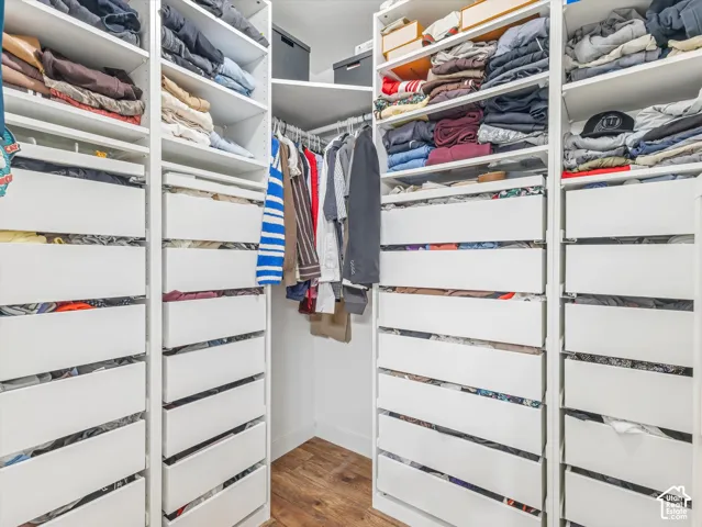 Custom white built-in cabinetry featuring multiple drawers and open shelving, complemented by a wood-finish floor and integrated hanging rods