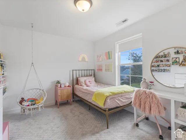 Neutral-toned carpeting, large window with muntin detailing, ceiling-mounted flush light fixture, and built-in desk surface
