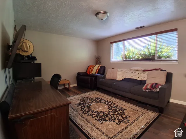 Room featuring dark-toned wood-finish flooring, a large horizontal window with slatted blinds, and a semi-flush mount ceiling fixture