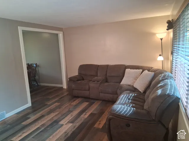 Neutral-toned interior space featuring wood-finish flooring, wide cased openings, and horizontal window blinds