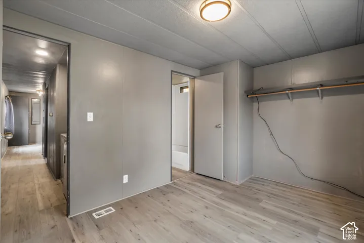 Neutral-toned interior featuring wood-finish flooring, panelled wall construction, built-in shelving, and a semi-flush mount ceiling fixture