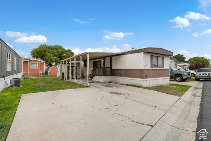 Exterior featuring horizontal siding, a covered carport, concrete driveway, and an attached storage structure
