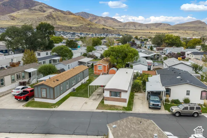 Aerial perspective of the residential area featuring paved driveways, covered parking structures, mature trees, and mountainous terrain in the background