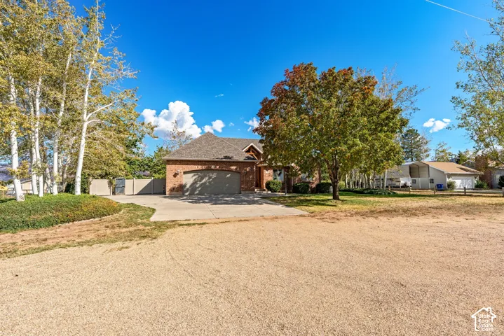 Brick exterior facade featuring a multi-pitched roofline, an attached multi-car garage, and a concrete driveway