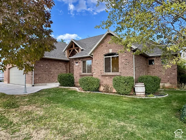 Brick exterior featuring a gabled roofline with timber truss detailing, an arched window entry, and an attached multi-car garage