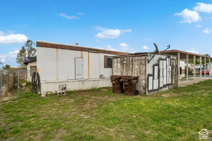Exterior lot featuring a metal-sided structure, a covered carport, and chain-link perimeter fencing