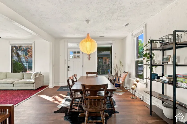 Open-concept interior featuring wood-finish flooring, crisp white wall finishes, multi-pane entry door, and a globe-style pendant light fixture