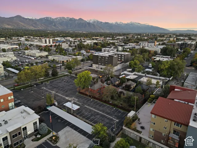 Aerial perspective featuring a paved parking lot with covered carports, mature landscaping, and an expansive mountain range backdrop
