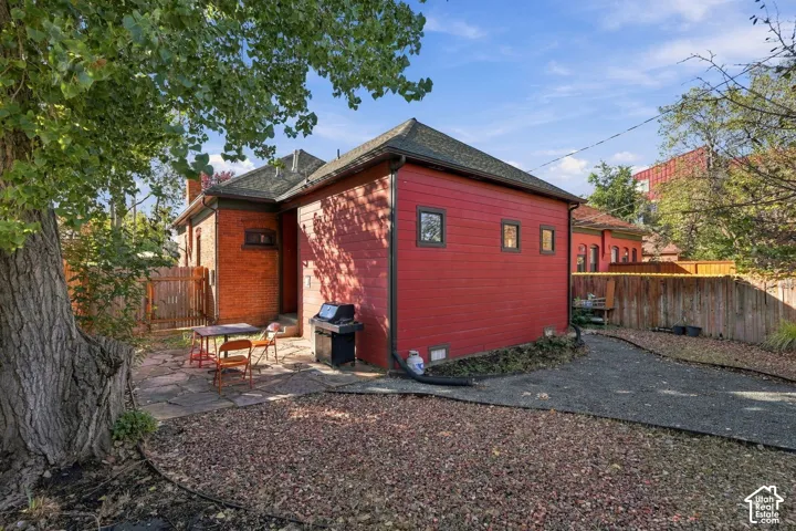Exterior facade featuring brick masonry and horizontal wood-finish siding, stone-paved patio, gravel grounds, and perimeter wood fencing
