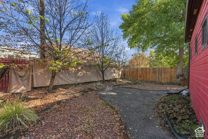 Backyard featuring a paved gravel patio, perimeter wood fencing, and mature trees