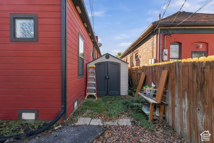 Exterior side yard featuring horizontal siding, a detached storage structure, and a wood privacy fence