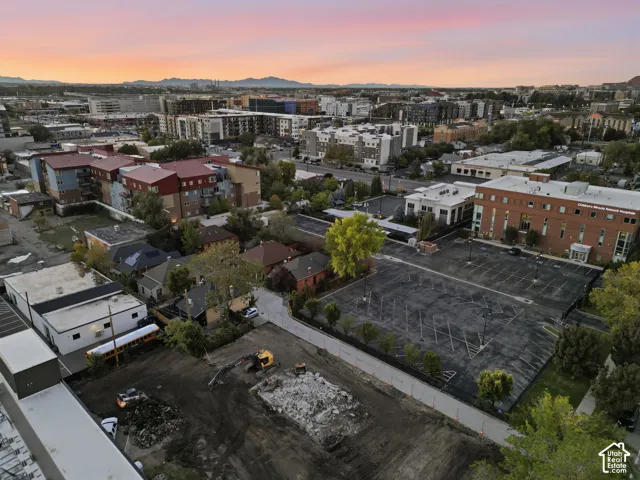 Aerial perspective featuring a cleared urban lot, expansive city skyline, mountainous backdrop, and established surrounding infrastructure