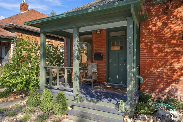 Red brick exterior featuring a covered front porch with painted wood columns, railing, and stairs, complete with a craftsman-style front door with glass transom
