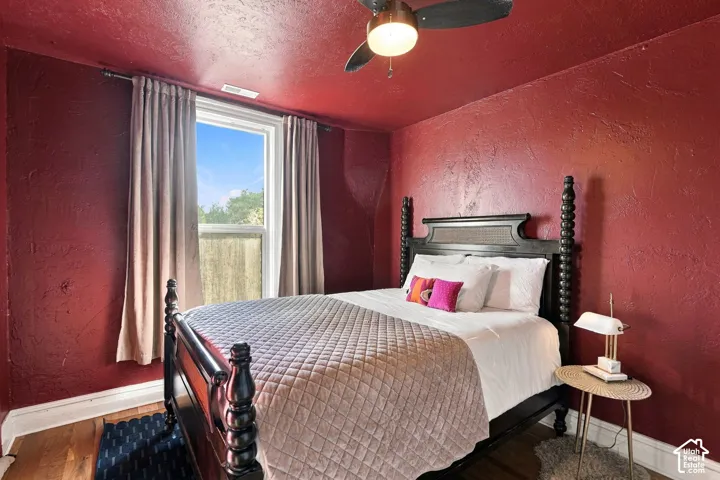 Room featuring textured wall finishes, wood-finish flooring, and a ceiling fan with integrated lighting
