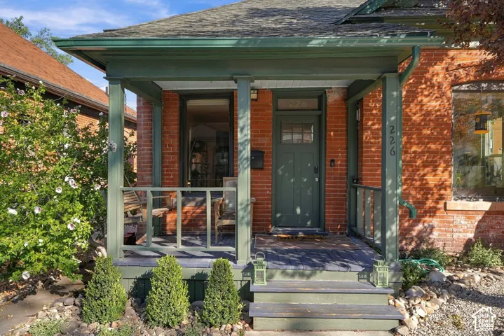 Brick exterior featuring a covered front porch, wooden support columns, a paneled door with glass inlay, and tiered wooden front steps