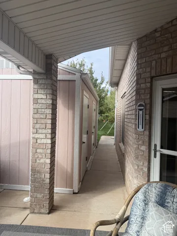 Covered patio with brick-clad support pillars, concrete walkway, and exterior masonry construction